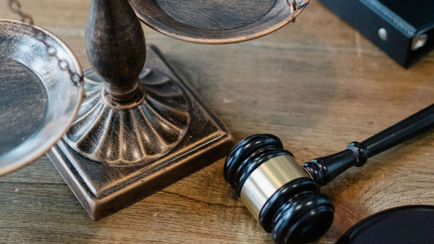 Balanza de la justicia y mazo de juez sobre una mesa de madera